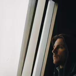 a young person looking out a window and staring outside