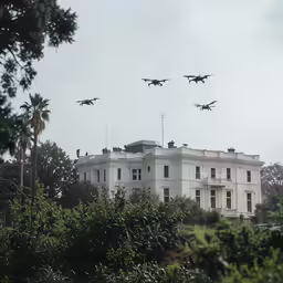 four air planes are flying above a mansion