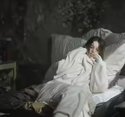 the girl is sitting in her bed and looking at something