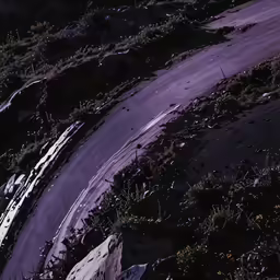 a lone snowboarder riding down a small hill in the sun
