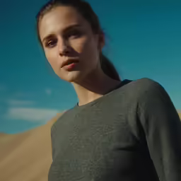 a young woman poses in front of a blue sky