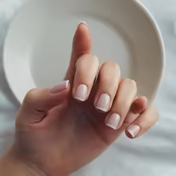 a close up of someones hand with a beige manicure