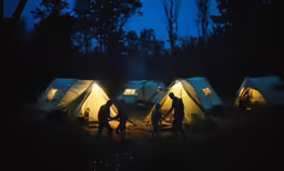 a group of people walking through tents at night