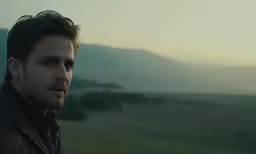 man in a brown leather jacket looking to the side