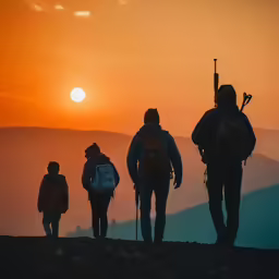 three people are on a hillside looking at the sunset