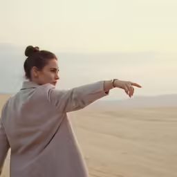 a woman pointing at something in the desert