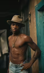 man with no shirt and a hat leaning against the wall