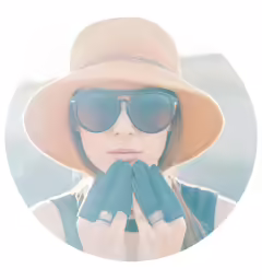 a woman in a hat and sunglasses with her hands clasped