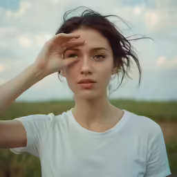 a woman in a white shirt and some clouds and grass