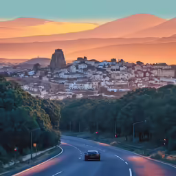 the city is sitting near a mountain during sunset