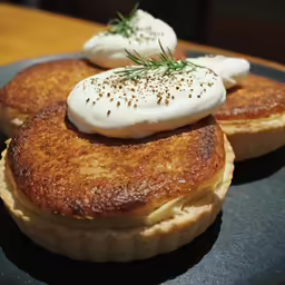 two small pancakes sitting on top of a black plate