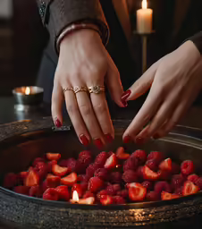 a close up of hands reaching for a strawberry