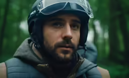 a man wearing a helmet standing outside near some trees