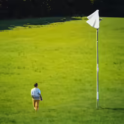 a person walking on a green field with a white flag