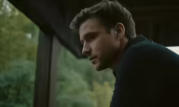 a man in a black sweater looks back