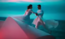 two people in white dresses dancing in front of a blue and pink background