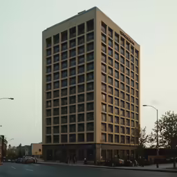 an empty street with several parked cars in front of a tall building