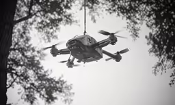 a helicopter being lowered by two ropes in front of trees