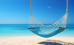 a blue hammock hanging over sand at the beach