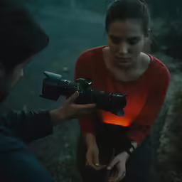 a person is holding a camera with an orange light on the lens