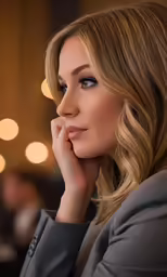 a woman with long blonde hair and a ponytail looks into the distance