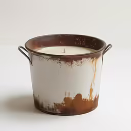 a white and brown metal bucket holds a lit candle