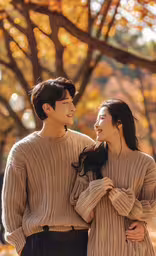 an image of couple laughing and hugging outside,a couple smiling together in front of leaves