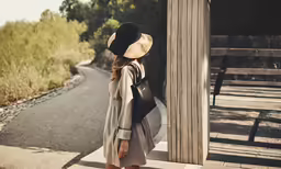 the woman is standing on the side walk looking out at the grass