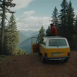 a yellow van parked in the mountains with a man sitting on top