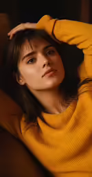 a woman wearing a mustard yellow sweater, posing for the camera