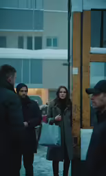 two people wearing winter clothes standing next to a building