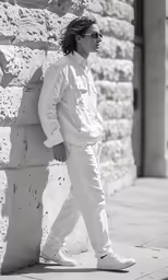 a man walking on the side walk with sunglasses on