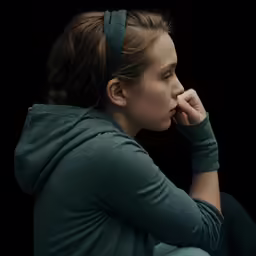 a person with a gray headband holding their face in her hands