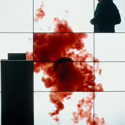 a man standing on the side of a building with red smoke in front of it