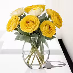 the yellow flowers are in the clear vase
