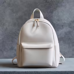 a white leather backpack sitting on top of a gray surface