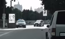a car and truck on a street with a billboard in the distance