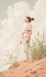 a woman wearing beige is walking in the sand