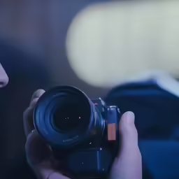 a camera man holding up a lens with his camera