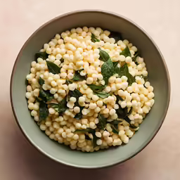 a bowl of corn with basil leaves in it