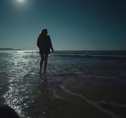 a young woman is walking on the beach