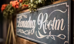 a sign on a wooden box holding some flowers