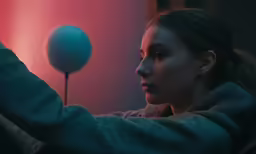 the woman is observing the blue object in the distance