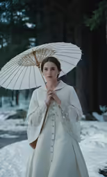 a woman dressed in a white wedding gown with an umbrella