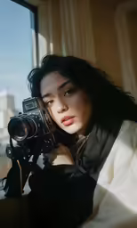 a young woman is taking pictures while sitting by a window