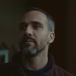 a man with beard and dark hoodie looking straight ahead