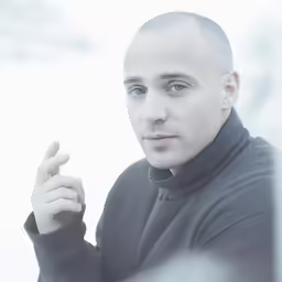 a bald man with a cigarette is looking at the camera