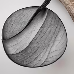 a gray and white leaf hanging on a wooden stick