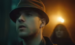 a man standing in a dark room wearing a hat