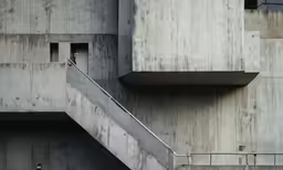 the man stands near a set of stairs, opening the windows and looking out